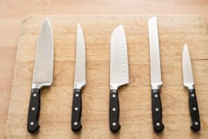 Cinco tipos diferentes de facas de cozinha alinhadas em uma bancada