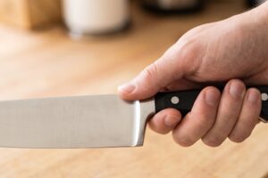 Mão segurando uma faca de chef com o punho apertado
